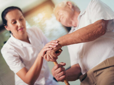 A health care professional assists an older patient.