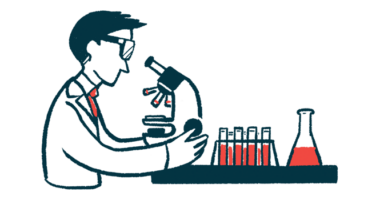 A scientist looks through a microscope on a table with a beaker and test tubes.