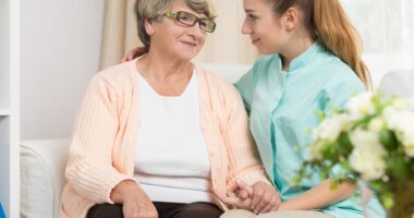 young female caregiver talking to elderly mother