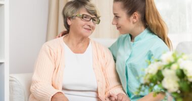 young female caregiver talking to elderly mother