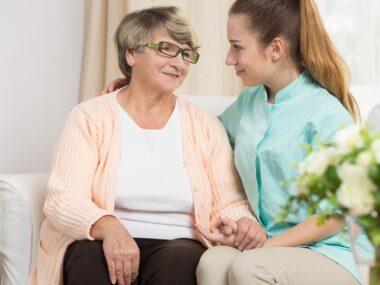 young female caregiver talking to elderly mother