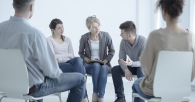 People sitting in chairs in a circle in a support group setting