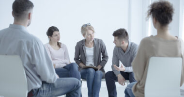 People sitting in chairs in a circle in a support group setting