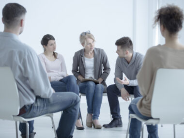 People sitting in chairs in a circle in a support group setting