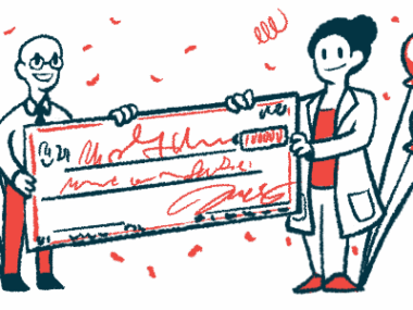 Two clinicians are seen holding either end of a giant check amid balloons and streamers.