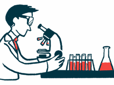 A scientist looks through a microscope on a lab table, alongside a beaker and a rack of test tubes.