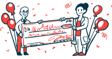 Two researchers each hold one end of a giant check.