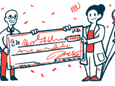 Two researchers each hold one end of a giant check.