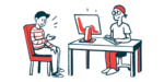 A patient talks to a clinician who is seated behind a computer monitor.