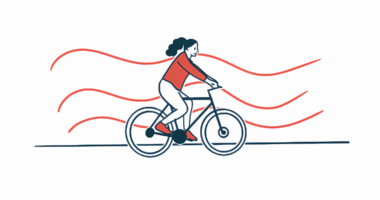 A woman in a red sweater rides a bicycle.