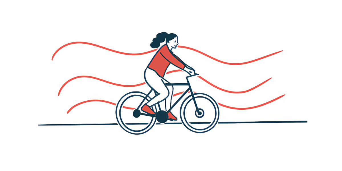 A woman in a red sweater rides a bicycle.